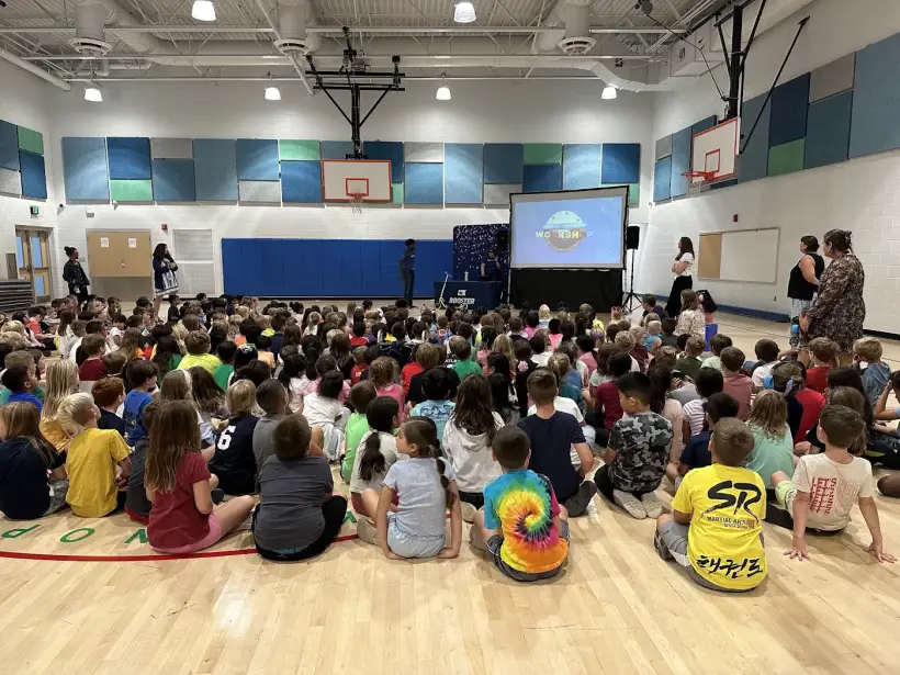 Students seated on the gym floor watching a presentation