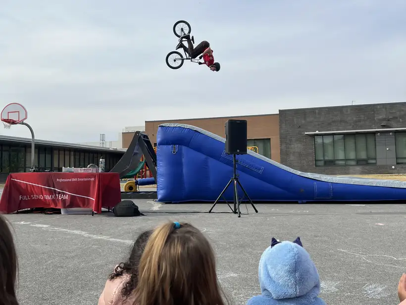 Edgewater students watching a BMX rider backflip above a ramp on the blacktop