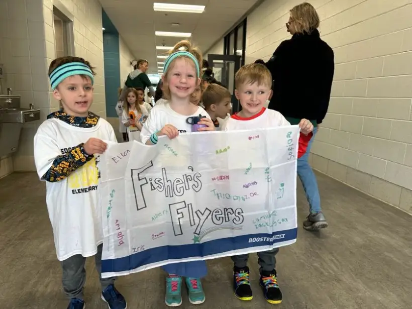 Three students holding up a hand-decorated class banner