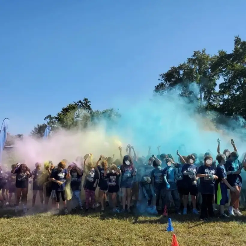 Students running through a cloud of blue colour powder at the Boosterthon
