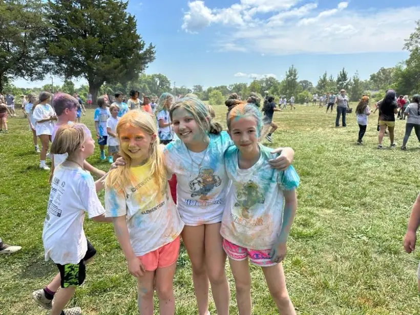Four students in colour-covered shirts standing together after the colour run