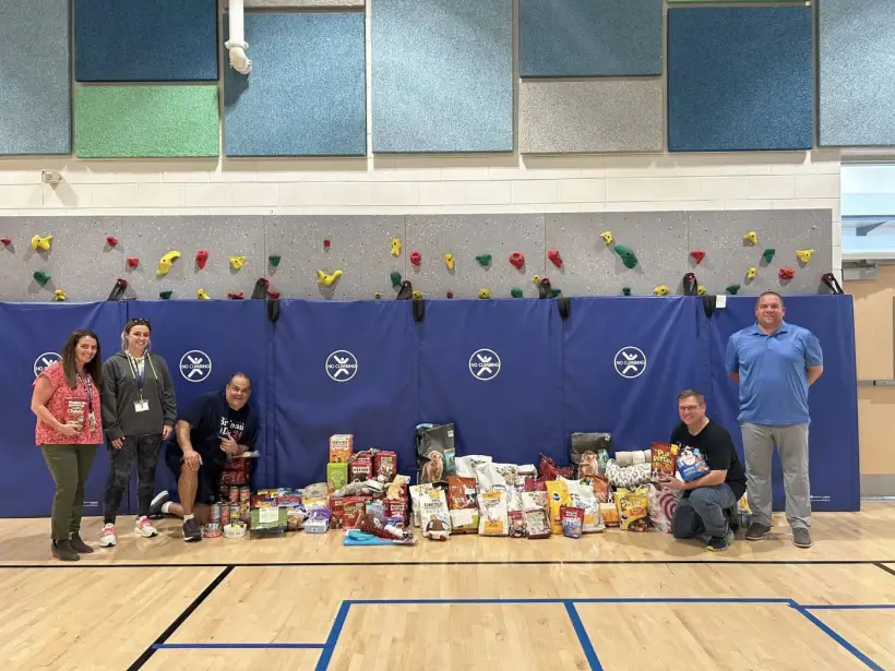 Volunteers standing behind tables of donated goods in the gym