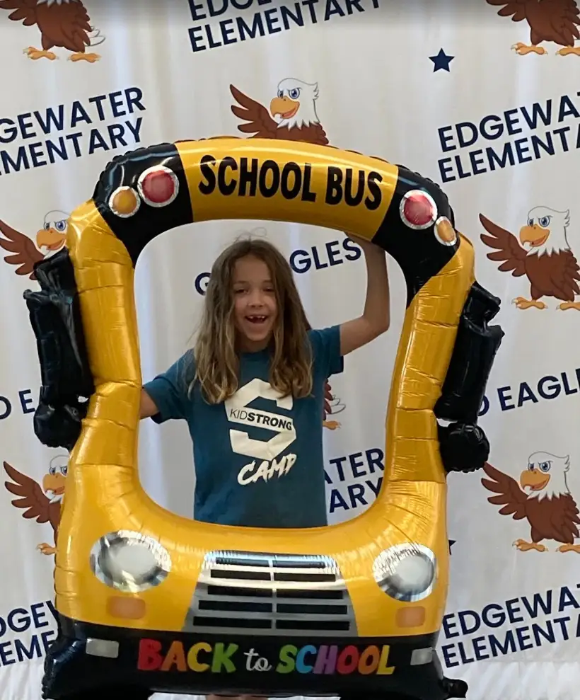 An Edgewater student grinning inside an inflatable school bus photo frame