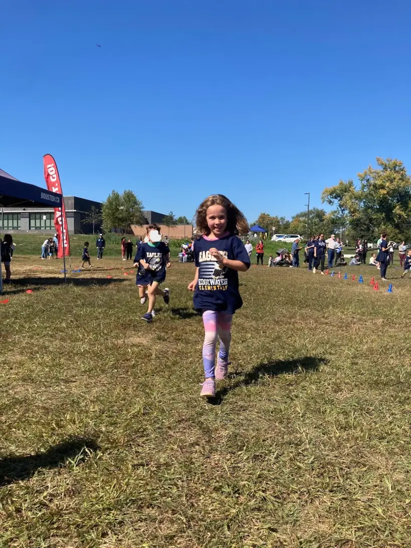A student running toward the finish line wearing her race bib