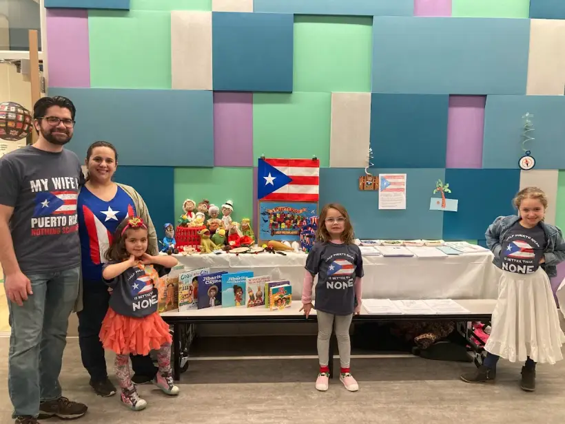 A family standing behind their Puerto Rico display table at International Night
