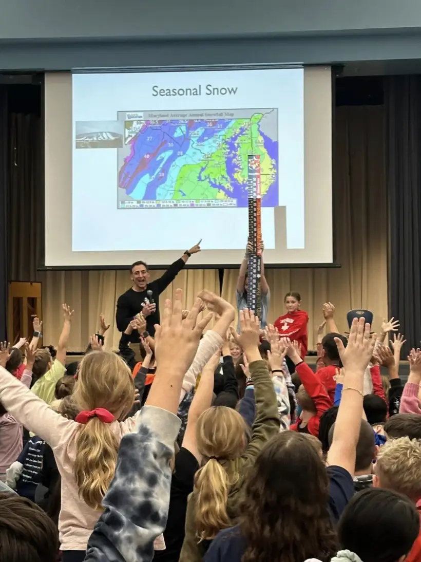 Edgewater students with their hands in the air during a school assembly
