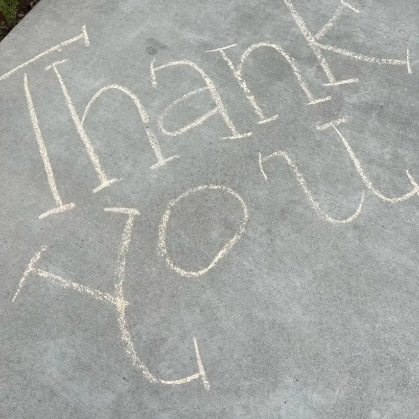 Thank you written in chalk on the sidewalk outside school